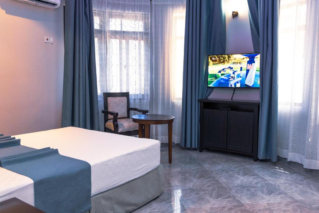 达累斯萨拉姆Velmont Hotel的配有电视和床的酒店客房