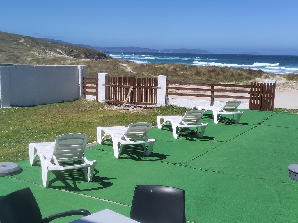 卡尔瓦略Coruña Backpackers Hostel的海滩上一组草坪椅