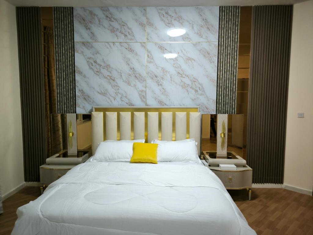 阿吉曼شقة فخمة وواسعة غرفتين luxury and big 2BR的卧室配有白色床和黄色枕头