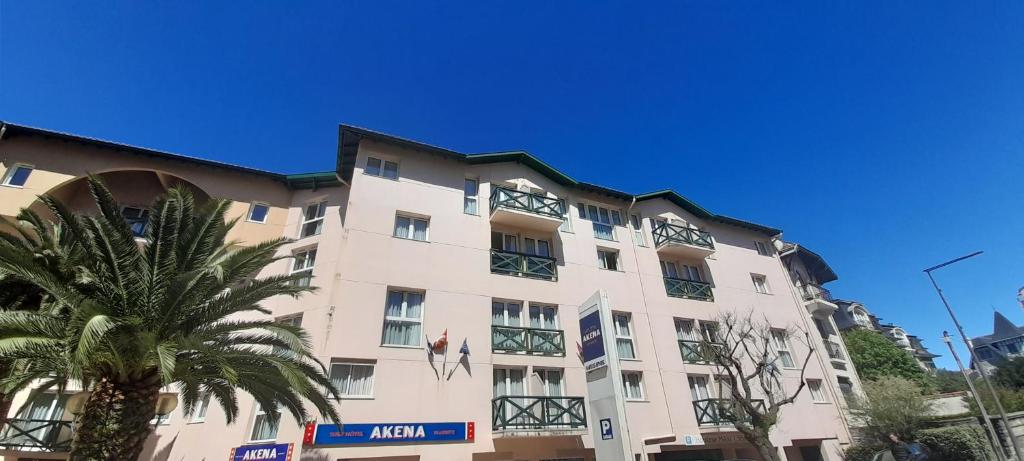 比亚里茨Hôtel AKENA Biarritz - Grande plage的前面有棕榈树的建筑