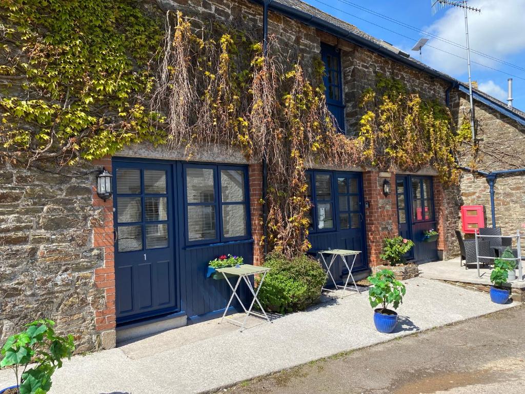 普里茅斯The Ivy Barn Holbeton的砖砌的建筑,有蓝色的门和植物