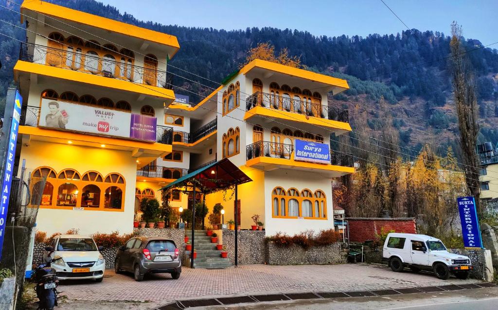 马拉里Surya International Hotel Manali near Mall Road的前面有汽车停放的建筑