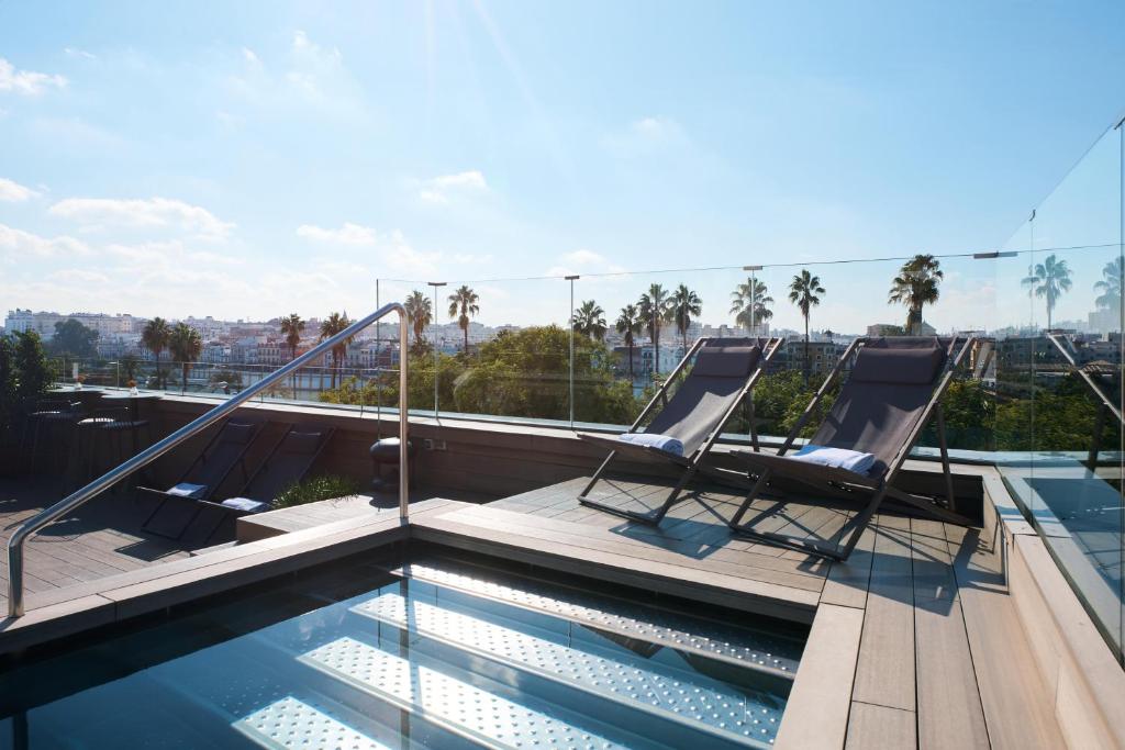 塞维利亚Hotel Kivir的屋顶上带两把椅子的游泳池