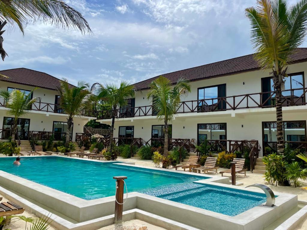 布韦朱Sand Beach Boutique Hotel的棕榈树酒店前的游泳池
