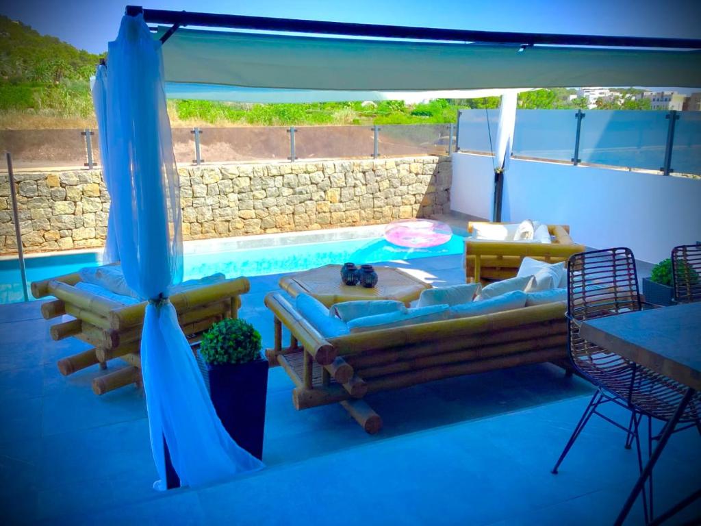 纽斯特拉塞诺拉耶苏斯WHITE HOUSE IBIZA的天井设有1个带沙发和蓝色遮阳伞的游泳池。