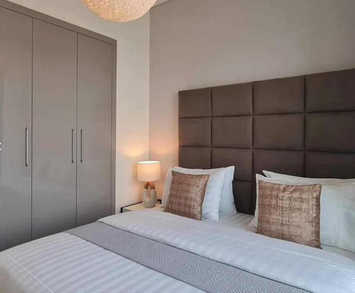 迪拜Dubai World Central Budget Apartments的一间卧室配有一张大床和大床头板