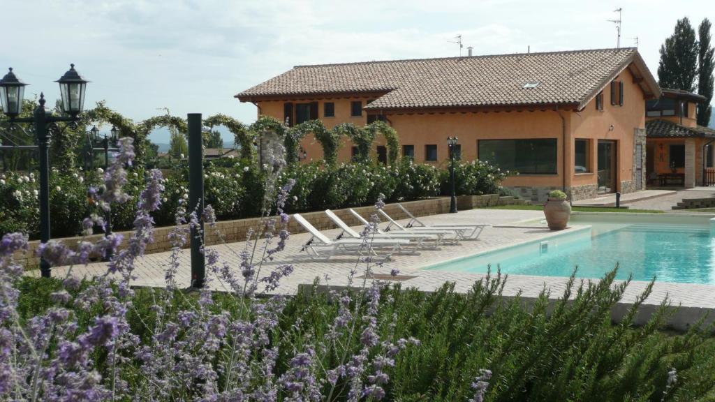 阿西西阿西西伊尔费尼勒住宿加早餐旅馆的一座带游泳池和紫色鲜花的房子
