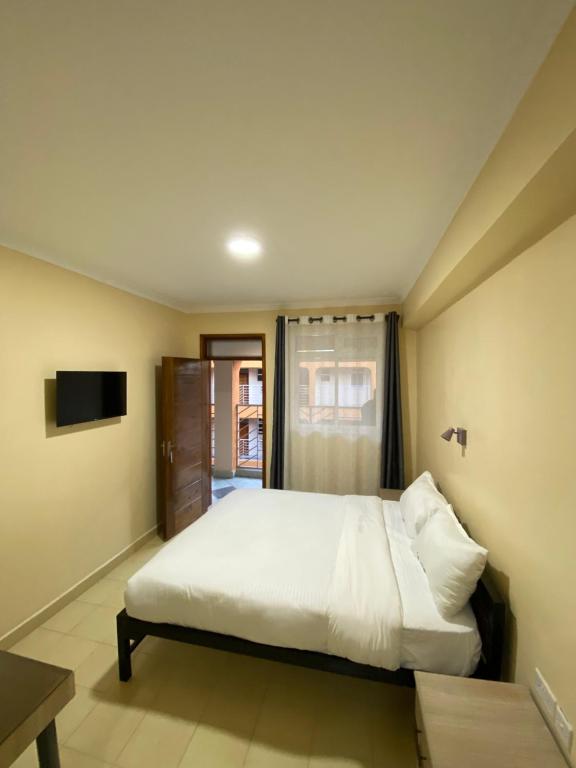 KiambuTodas Hotel的卧室配有白色的床和电视。