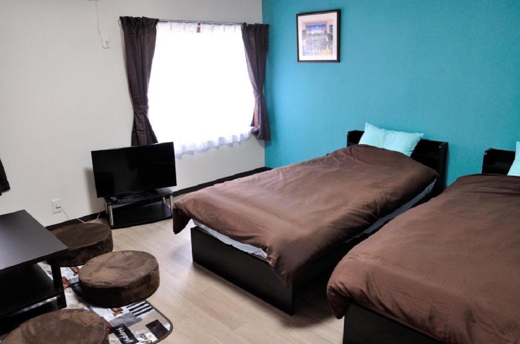 长滨市Minpaku KEN HOUSE - Vacation STAY 60980v的一间卧室设有两张床、一台电视和一扇窗户。