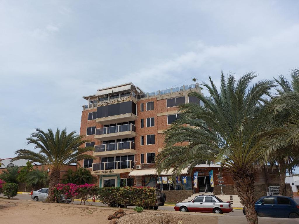 波拉马尔Hotel Yaque Club的一座高大的建筑,前面有棕榈树