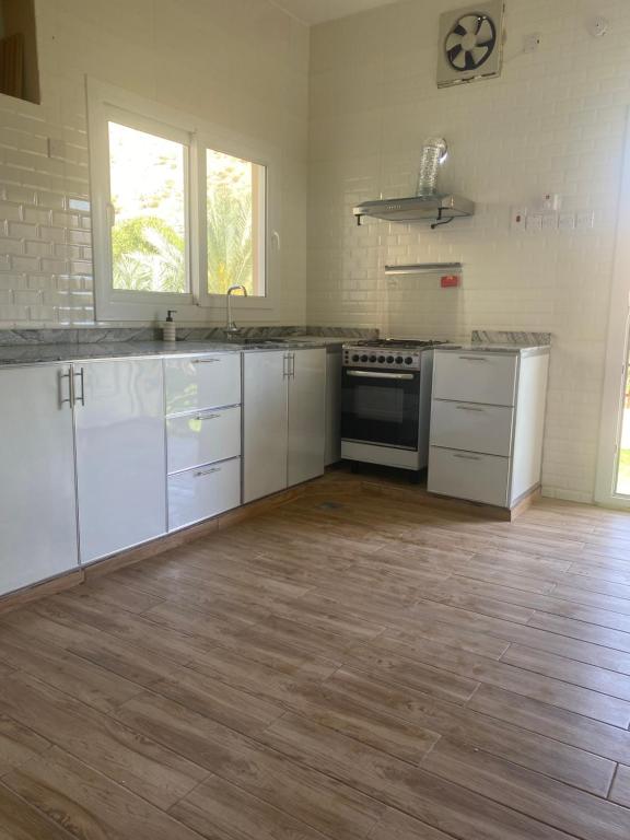 Dawwahإستراحة وادي بني خالد的厨房铺有木地板,配有白色橱柜。