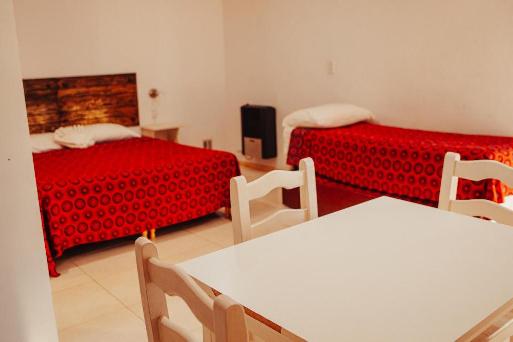 RealicóHOTEL REALICO的一间设有两张床和一张桌子及椅子的房间