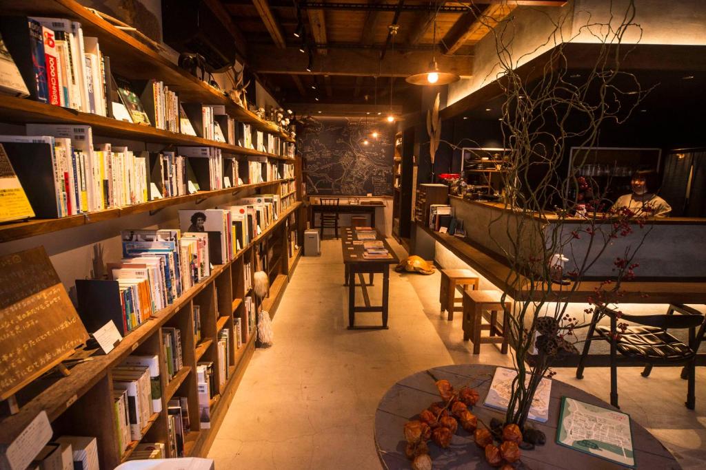丰冈市Book & Guesthouse Hitotomaru的书架上藏满了书的图书馆