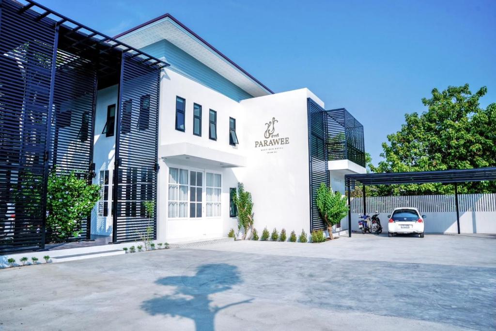 清莱โรงแรม ปารวี บูทีค เชียงราย (Parawee Boutique Hotel)的停车场内有停车位的白色建筑