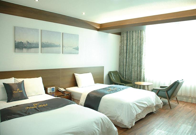 固城郡Prince hotel的酒店客房设有两张床和窗户。