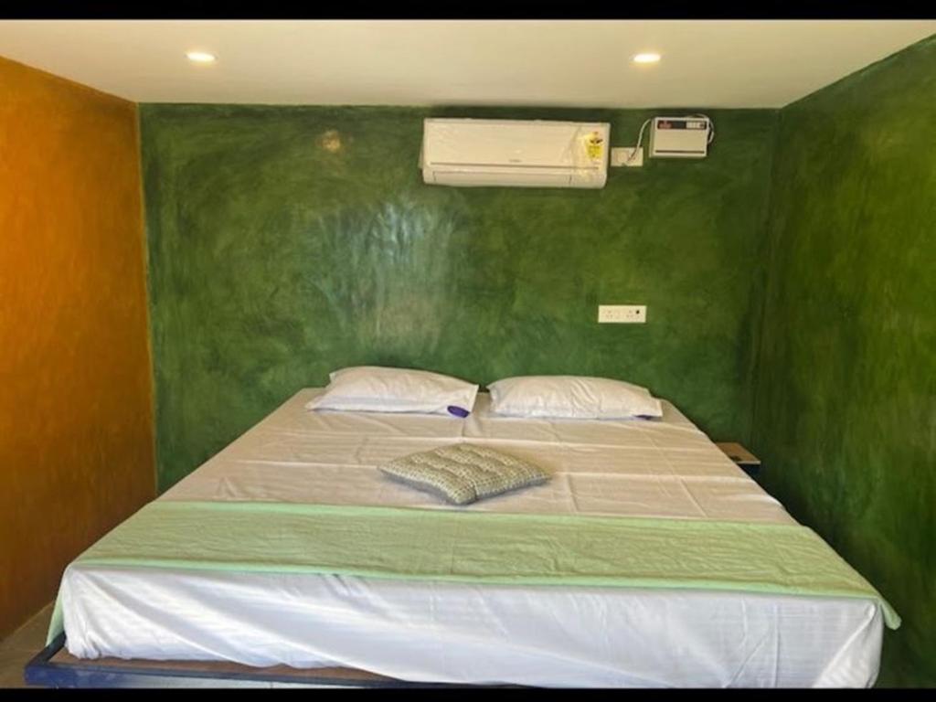 蓬蒂切里Nature Zone Resort的一间卧室设有一张带床铺的绿色墙壁