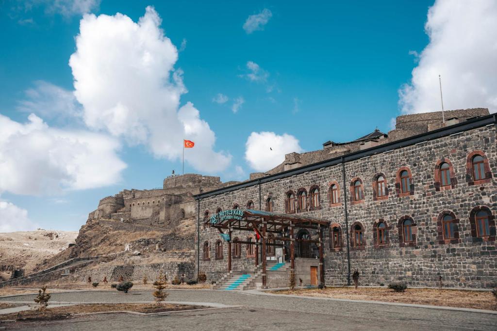 卡尔斯Ve Hotels Beylerbeyi Sarayı的山顶上悬挂着旗帜的建筑