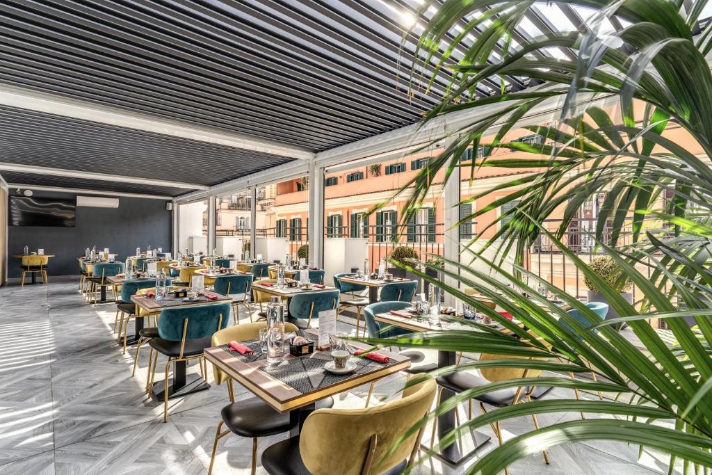 罗马CC Palace Hotel的一间设有桌椅的餐厅,以及一间种植了植物的餐厅