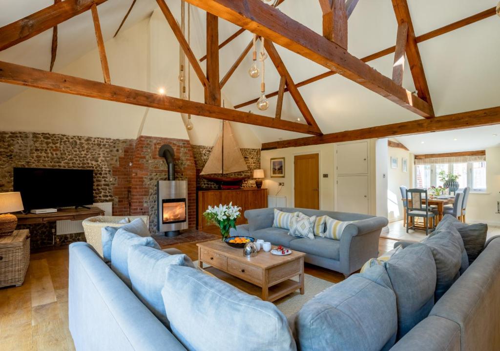 布莱克尼Boat Barn Cottage的大型客厅设有蓝色的沙发和壁炉