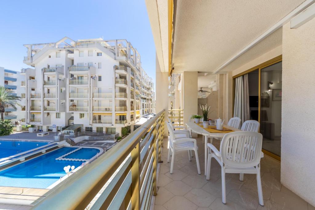 萨洛诺维特阿尔萨公寓的一个带桌椅的阳台和一个游泳池