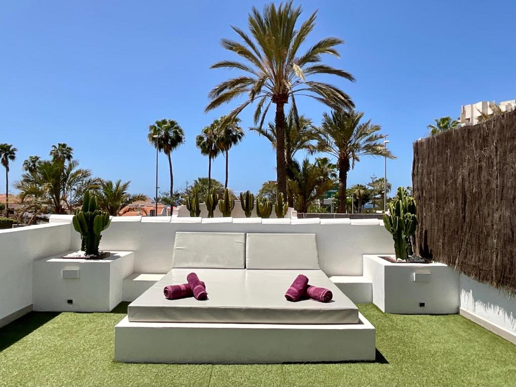 美洲海滩Las Americas Luxury Low-Cost Apartment with Terrace & Views的天井上的白色沙发,上面有粉红色的鞋