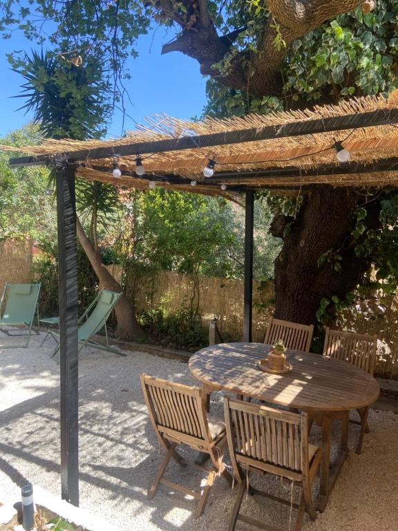 耶尔Rez de villa avec jardinet proche de la plage的凉棚下的一张木桌和椅子