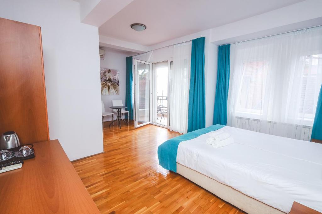 奥赫里德AMMOTTI Hotel and Apartments的一间卧室配有一张带蓝色窗帘的床,铺有木地板