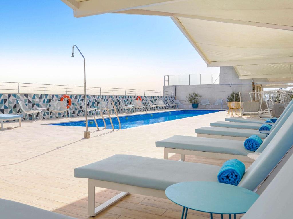 塞维利亚Novotel Sevilla的一个带蓝色躺椅的游泳池和一个游泳池