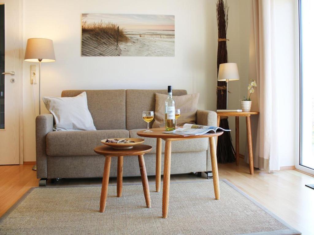 博尔滕哈根Residenz Haffblick, Wohnung 37的客厅配有沙发和带酒杯的桌子