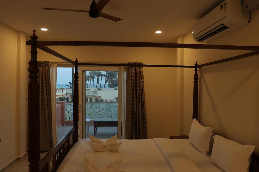 蓬蒂切里PALM PARADISE Beach Resort的一间卧室设有一张带大窗户的天蓬床