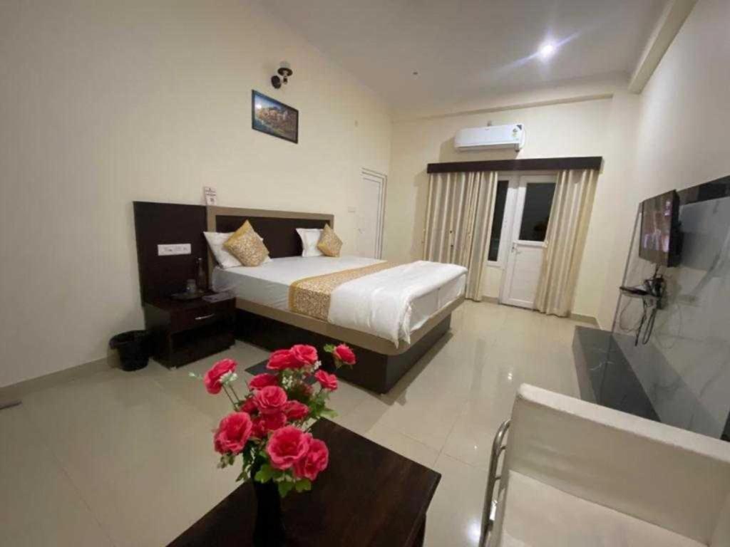 瓦拉纳西Hotel Nath Palace Chunar Road Varanasi - Luxury Room - Excellent Service Recommended的一间卧室配有一张床和一张鲜花桌