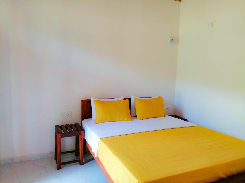 马特勒Sinharaja Cabana的一间卧室配有一张带两个黄色枕头的床