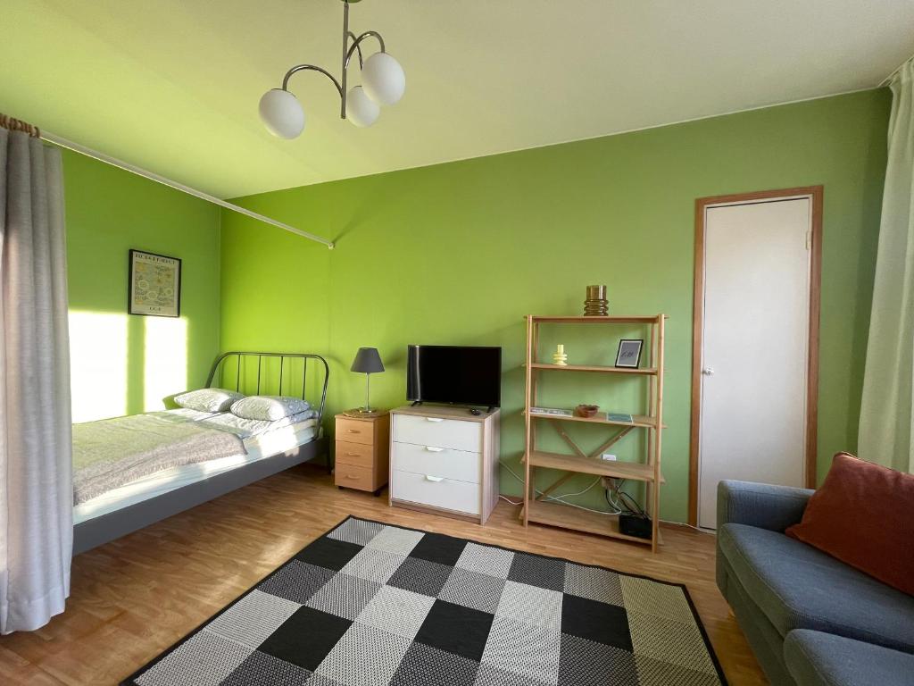图尔库The Golden Glow Apartment Turku的一间卧室设有绿色的墙壁、一张床和一张沙发