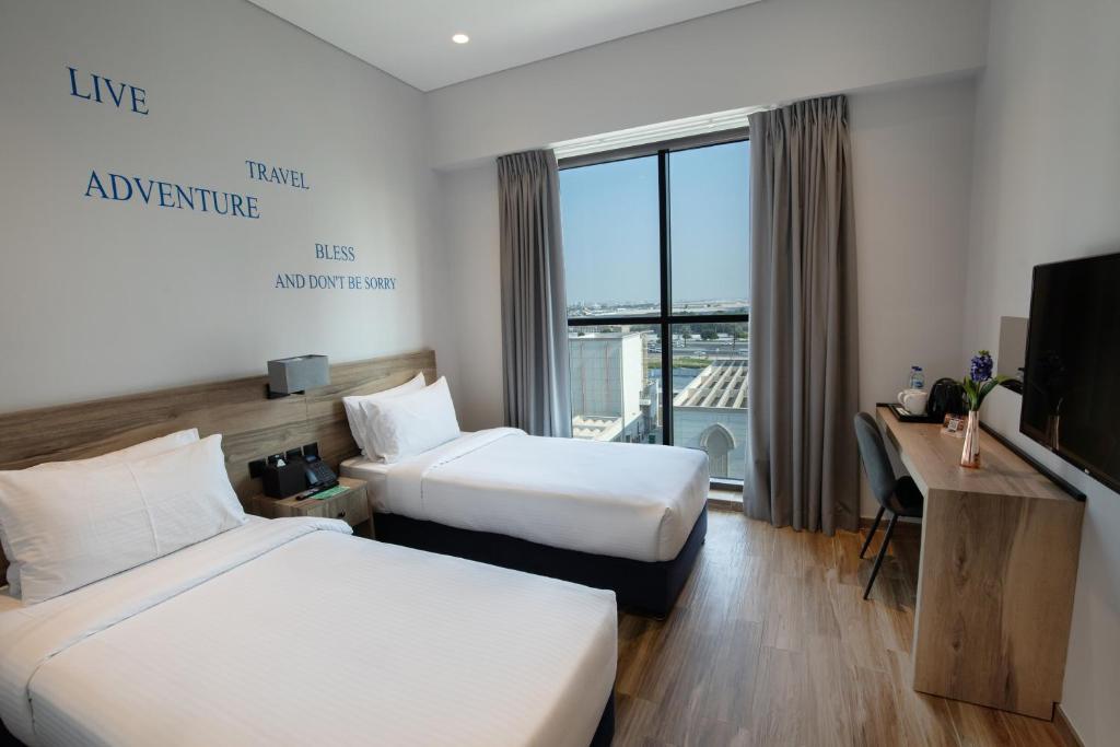 迪拜Kingsgate Canal Hotel by Millennium的酒店客房设有两张床和电视。