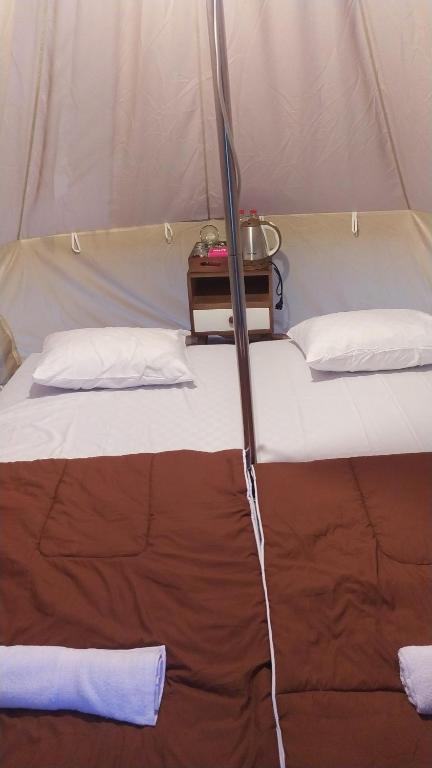 KejajarSunCampGround Glamping的帐篷内的一张床位,配有两个枕头和一张桌子