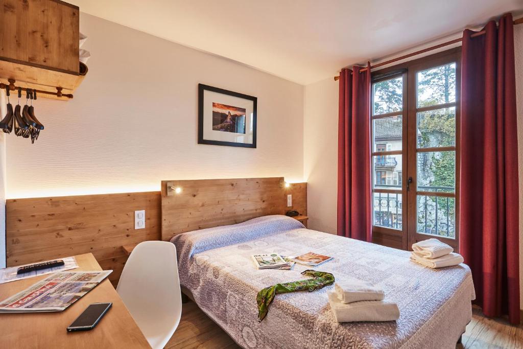 克吕斯Cit'Hôtel Le National的一间卧室配有一张床、一张桌子和一张桌子