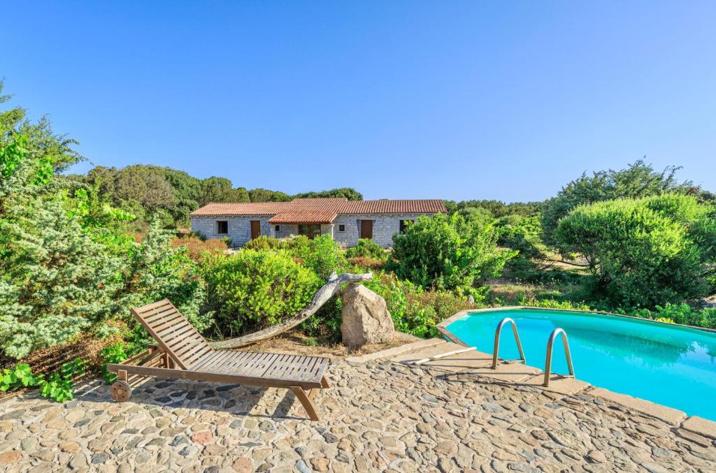 巴德希Residence surrounded by greenery with swimming pool in Badesi just 300 meters from the sea的一个带椅子的庭院和一个游泳池