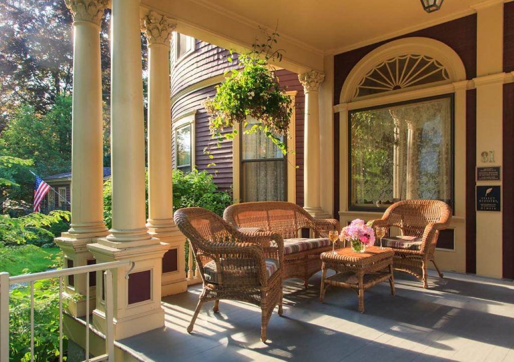 罗克兰Berry Manor Inn的门廊配有藤椅和鲜花桌