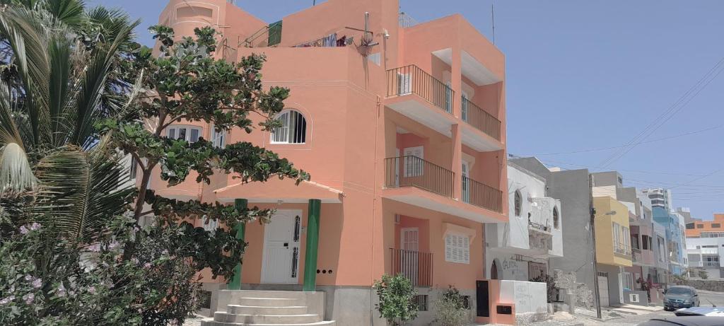 明德卢Laginha Beach Guest House的一条棕榈树街道上的粉红色建筑