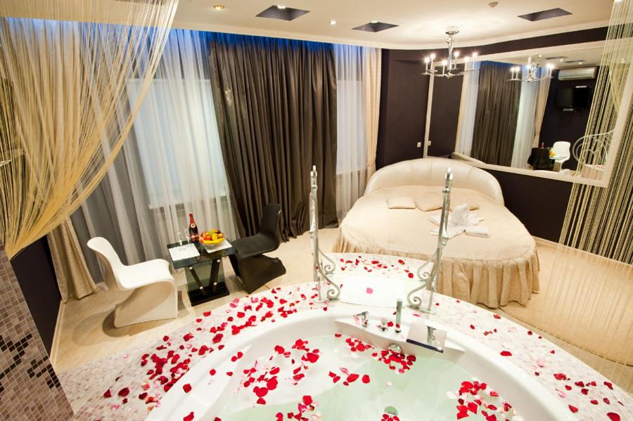 哈尔科夫风格酒店的一间卧室配有一张床和一个布满红花的浴缸