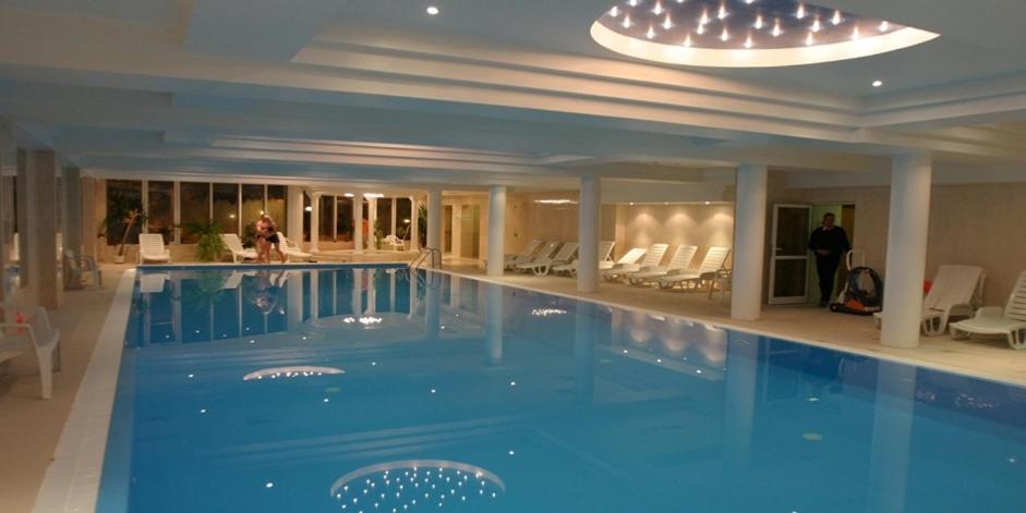 罗兹考尼大使酒店的酒店设有一个大型游泳池,周围的人都站在游泳池旁