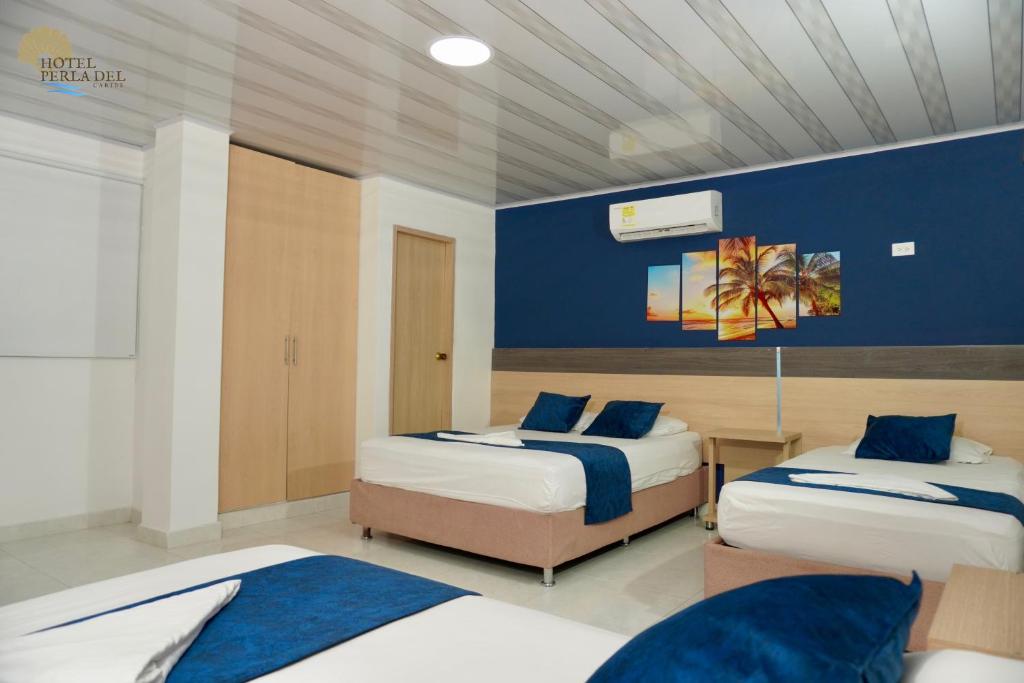 圣玛尔塔Hotel Perla del Caribe的一间卧室设有两张床和蓝色的墙壁