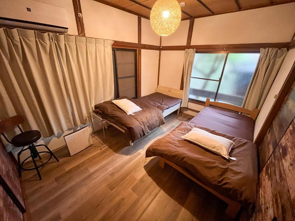 汤河原町温泉街の入り口にあるゲストハウス SLOW HOUSE yugawara的客房设有两张床和吊灯。