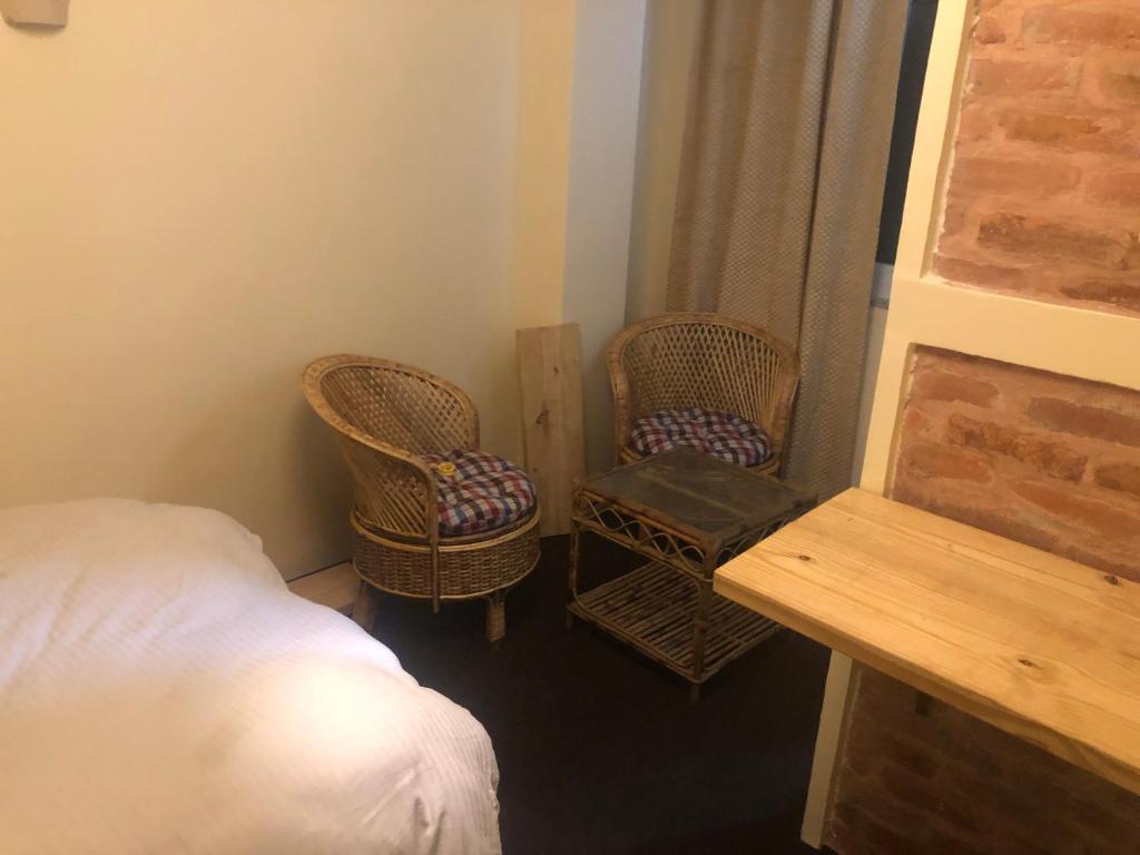 帕坦Newari homestay的一间卧室配有两把椅子、一张床和一张桌子