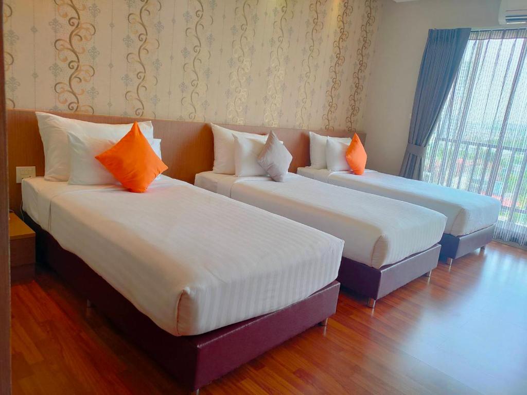 合艾东娜奥大酒店的两张带橙色枕头的床
