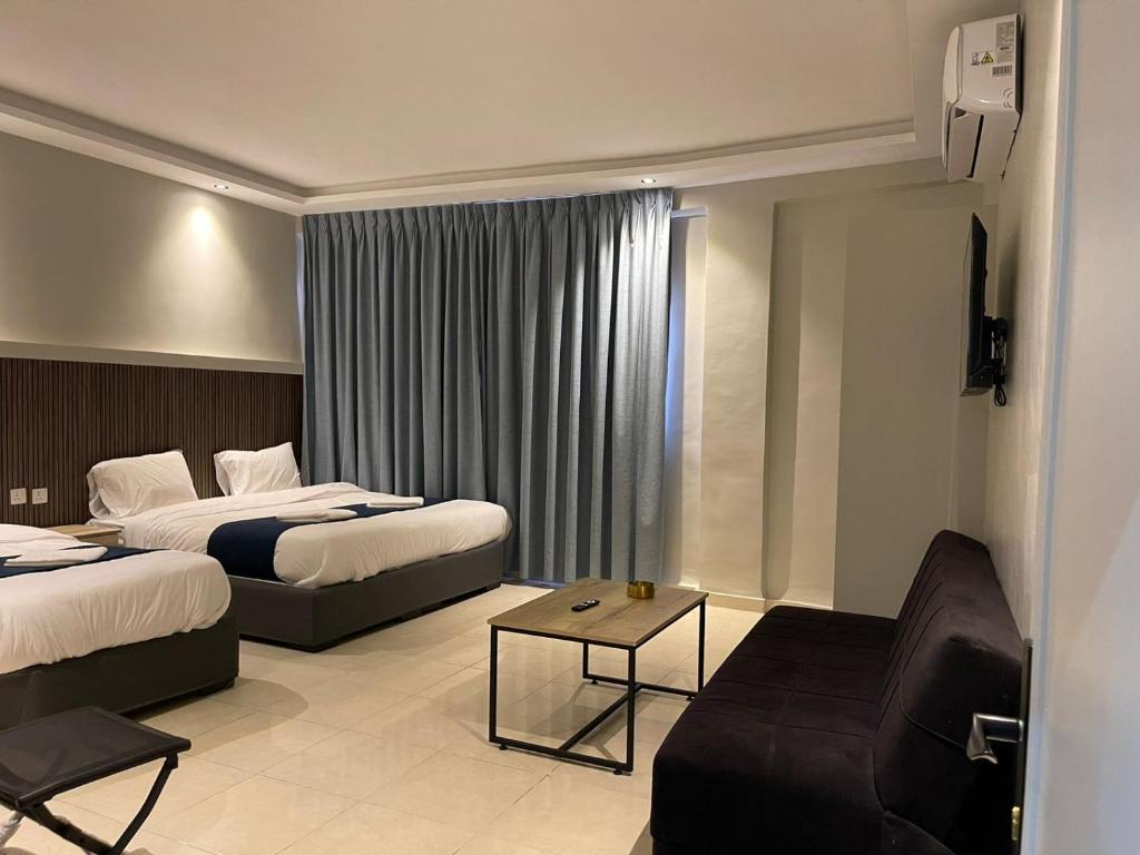 亚喀巴Aladnan hotel的酒店客房,设有两张床和一张沙发