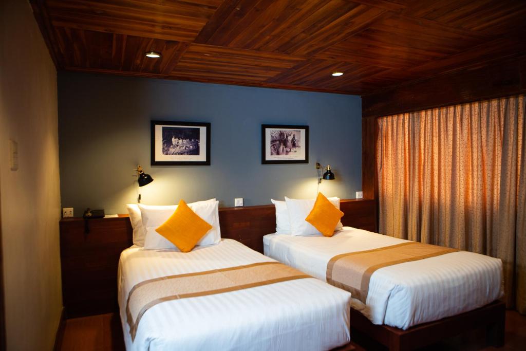 巴色Pakse hotel & Restaurant的蓝色墙壁客房的两张床