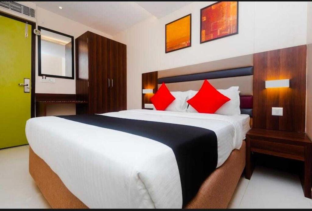 孟买Hotel Regal International - Near Mumbai International Airport Andheri East的卧室配有带红色枕头的大型白色床