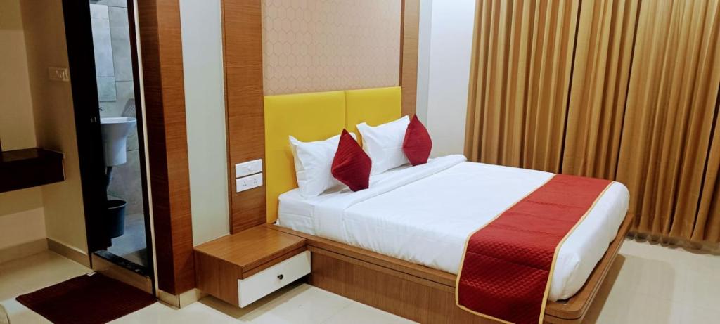 蒂鲁帕蒂HOTEL ORCHID VISTA的一间卧室配有一张带红色枕头的大床