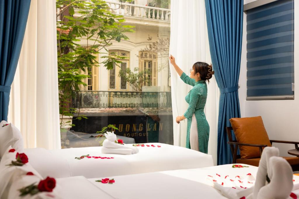 河内Casa Valentina Hanoi Hotel的女人在向酒店房间的窗户看
